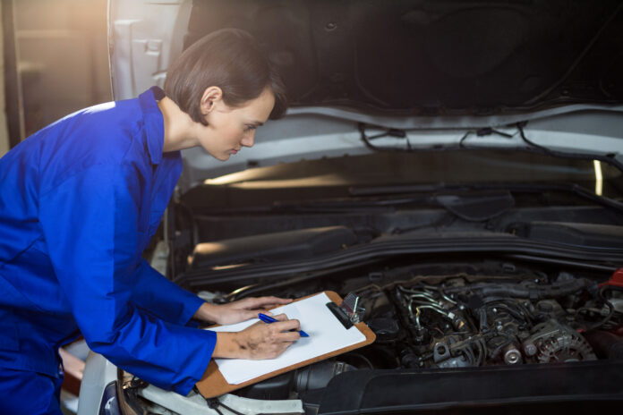 Mecânica fazendo checklist de manutenção automotiva.