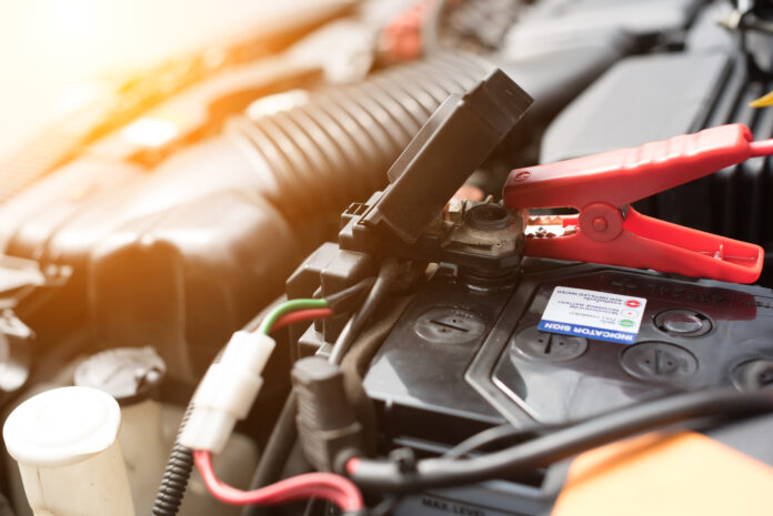 Teste de bateria de carro com cabo conector em um motor aberto.