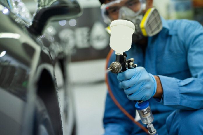 Profissional utilizando pistola de pintura automotiva para proteger a pintura do carro.